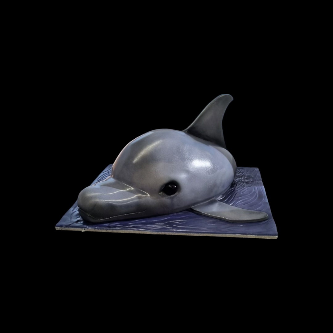 Realistic sculpted dolphin cake with detailed gray fondant design, resting on a textured blue ocean-inspired base, perfect for marine or ocean-themed celebrations, displayed against a black background."