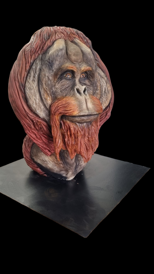 "Hyper-realistic orangutan sculpted cake with intricate detailing of facial features, textured fur, and lifelike expression, displayed on a black base against a solid black background.