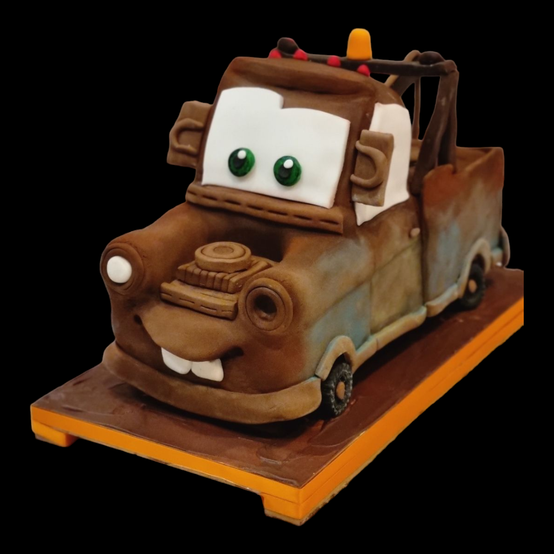 "Tow Mater sculpted cake inspired by the Cars movie, featuring realistic brown fondant details, big green eyes, and a cheerful smile, displayed on an orange and brown base with a black background."